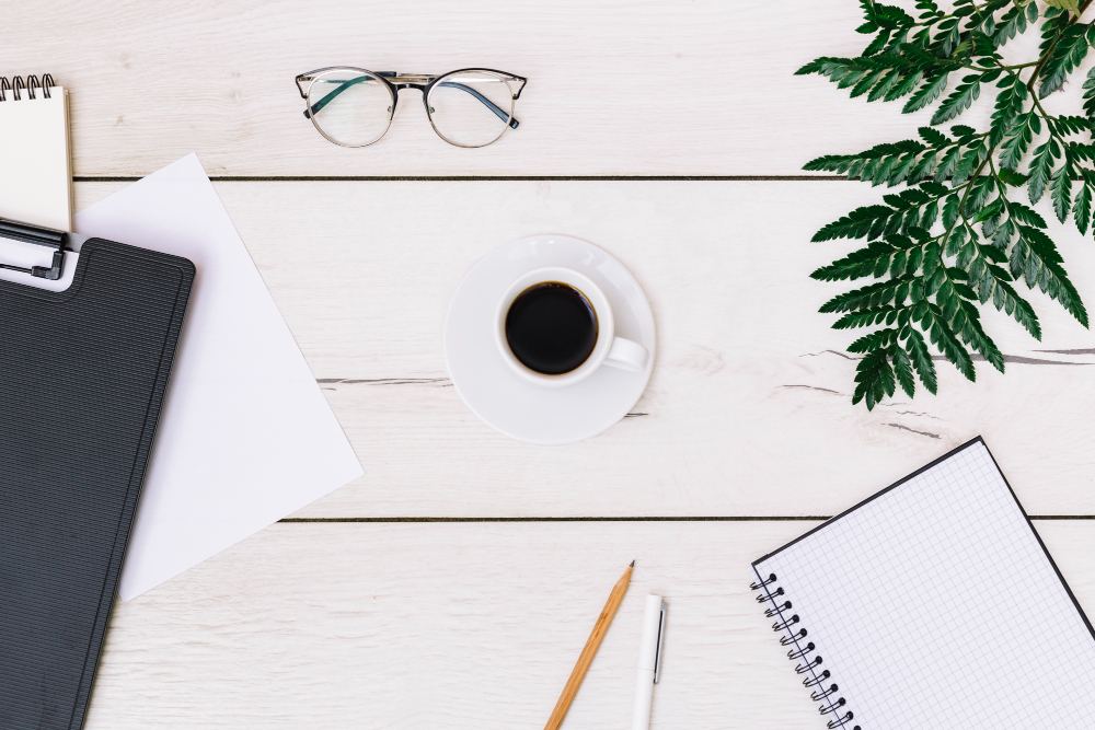 Bureau de travail organisé : ordinateur, café et plante verte